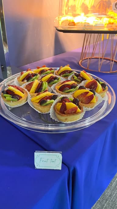 Round platter of fruit tarts with a labelled buffet card
