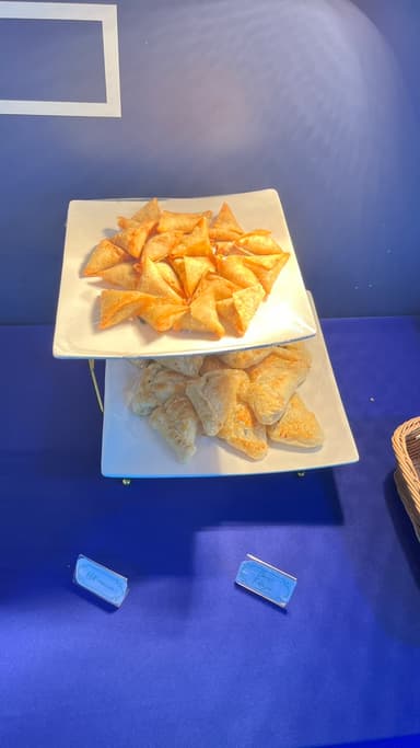 Two-tier stand of golden samosas and puff pastries
